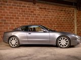 a silver sports car parked in front of a brick wall