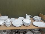 a lot of white plates and bowls on a shelf