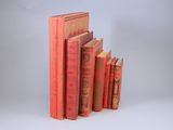 several red books are stacked on top of each other on a white surface