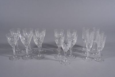 twelve crystal wine glasses lined up in a row on a white surface