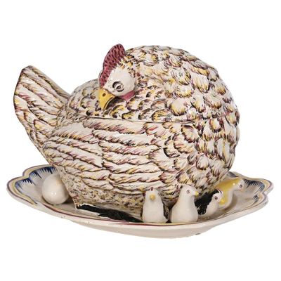 une poule posée sur une assiette sur laquelle se trouvent des œufs
