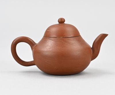 théière marron avec couvercle sur un support blanc, sur fond blanc