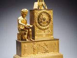 a gold clock with a statue on top of it