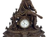 une statue en bronze représentant un homme assis sur un banc, avec une horloge