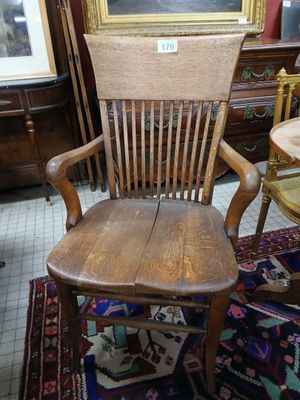 a wooden chair sitting in a room with a painting on the wall