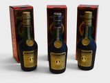 trois bouteilles d'alcool sont posées les unes à côté des autres sur une table