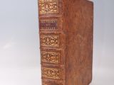 an old brown book with gold trim sitting on top of a white surface