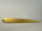 gold plated knife on a white surface with a gray background
