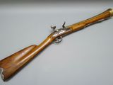 a rifle with a wooden handle on a white surface