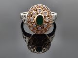 gros plan d'une bague avec une pierre verte entourée de diamants