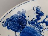 a blue and white plate with flowers and leaves on it