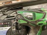 a green and black corded drill on a table