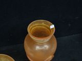 a brown vase sitting next to a bowl on a black surface