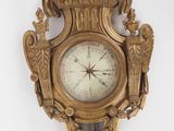 une horloge en or accrochée au mur, sur laquelle sont représentés deux oiseaux