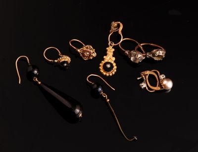 a group of gold and black earrings on a black surface