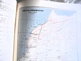 un livre ouvert, sur lequel figure une carte, posé sur un lit