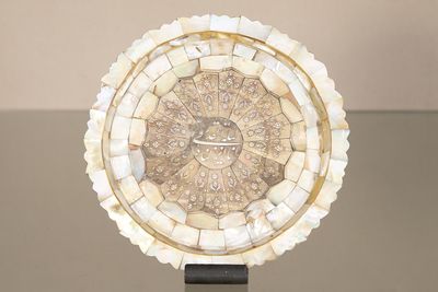 a clock made of shells on a stand on a table