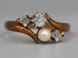 un gros plan sur une bague en or sertie d'une perle et d'un diamant