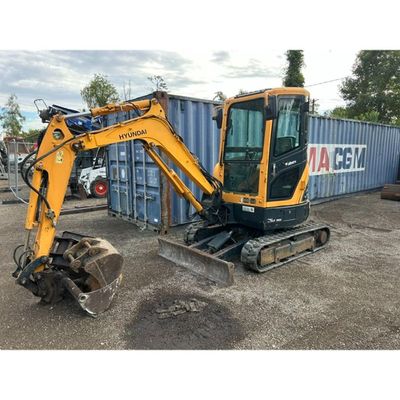an image of a small excavator parked in front of a shipping container