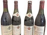 quatre bouteilles de vin sont alignées sur une surface blanche