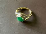 une photo d'une bague sertie d'une pierre verte posée sur une table