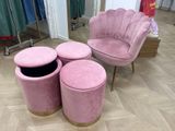 une chaise rose et trois tabourets devant un miroir