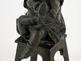 une petite statue représentant un enfant assis sur un tabouret