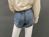 the back view of a mannequin mannequin wearing a beige shirt and denim shorts