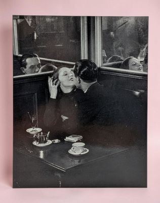photographie en noir et blanc d'un homme embrassant une femme à une table