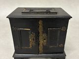 une vieille armoire en métal noir à deux portes, avec un tiroir sur le dessus