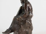 bronze statue of a woman sitting on a rock
