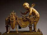 bronze statue of a child on a table with a basket of flowers