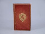 an old red book with a gold emblem on it