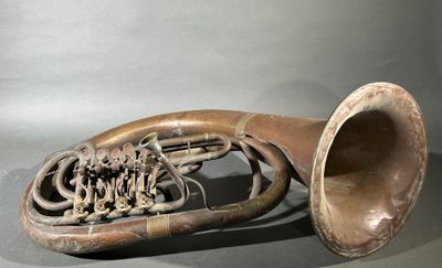 an old french horn sitting on a gray surface
