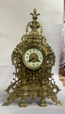 une horloge dorée posée sur une table, sur fond blanc