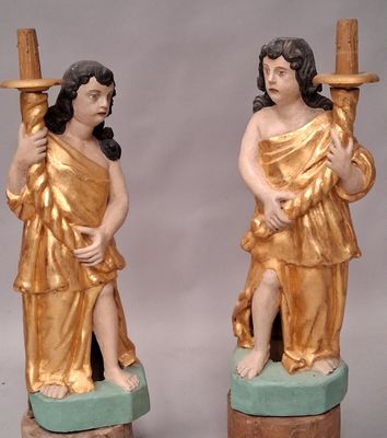 une paire de statues représentant un homme et une femme tenant une bougie