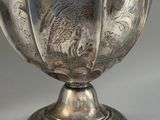 silver plated vase with floral design on pedestal on grey background