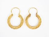 une paire de boucles d'oreilles en or sur fond blanc