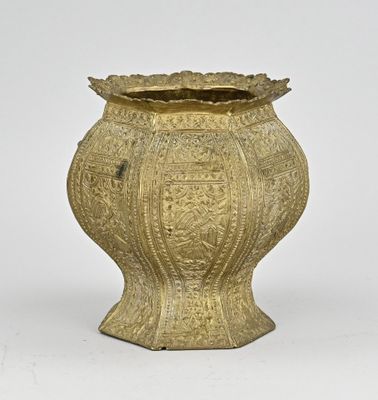 un vieux vase doré posé sur une surface blanche