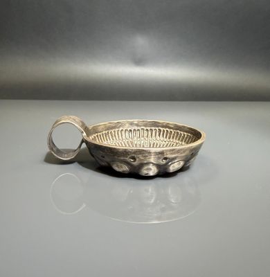 a silver bowl with a handle on a table