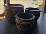 trois grands pots posés sur une table devant une fenêtre