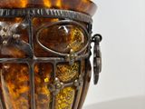 a brown vase with a metal handle on a table
