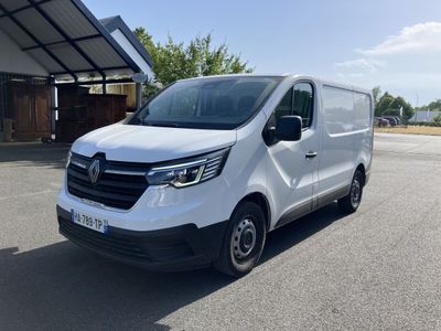 une camionnette blanche garée sur un parking à côté d'un bâtiment