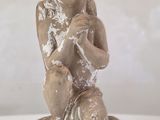 une petite statue représentant un enfant assis sur un bloc