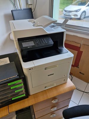 une imprimante posée sur un bureau près d'une fenêtre