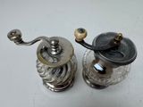 two silver pepper grinds on a white table