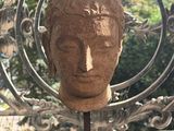 a statue of a head on a stand in front of a fence