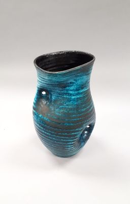 a blue and black vase sitting on a white surface