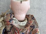 a pink vase sitting on top of a pile of clothes