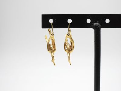 une paire de boucles d'oreilles en or posée sur un support noir